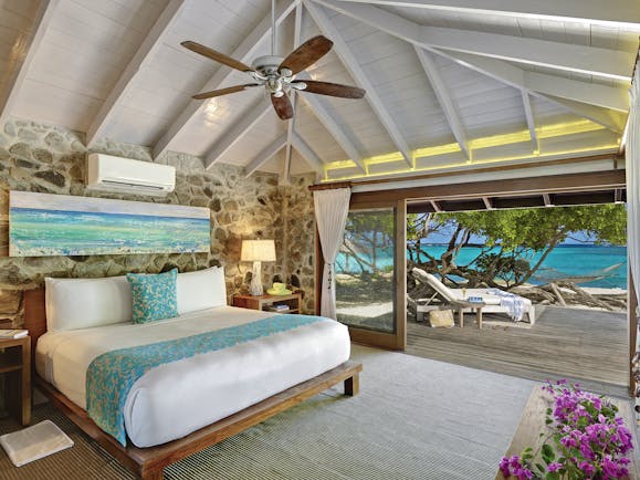 Petit St Vincent beach villa bedroom bed doors leading to decking beach views