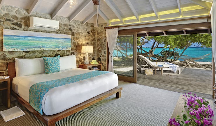 Petit St Vincent beach villa bedroom bed doors leading to decking beach views