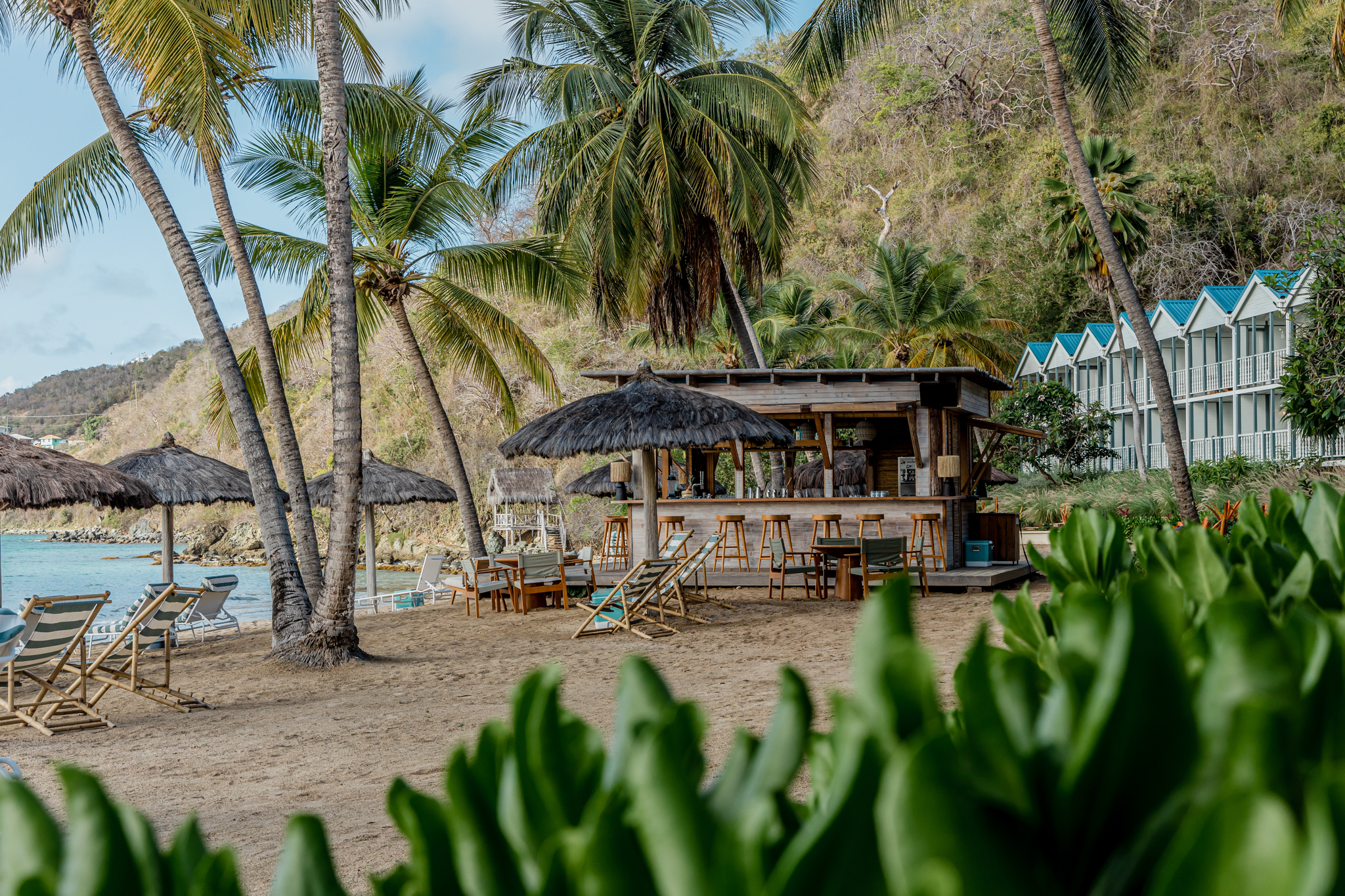 Soho Beach House Canouan beach bar hut with wooden roof and sun loungers and rustic parasols by the sea