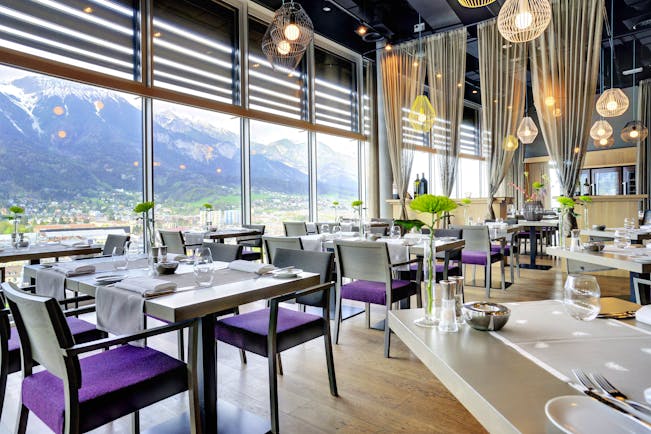 Adlers Hotel Austria Restaurant tables set up for food with large glass windows in the background looking out to mountains in the background