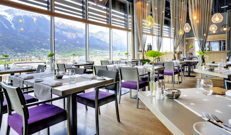 Adlers Hotel Austria Restaurant tables set up for food with large glass windows in the background looking out to mountains in the background