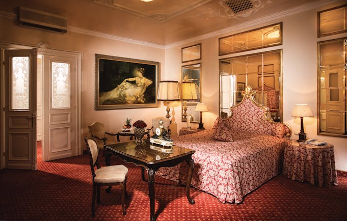 Hotel Bristol Salzburg junior suite with red colour scheme, large mirrors and gold framed paintings