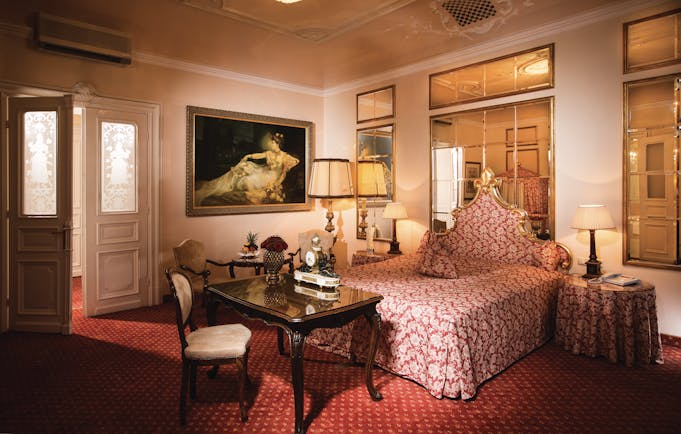 Hotel Bristol Salzburg junior suite with red colour scheme, large mirrors and gold framed paintings