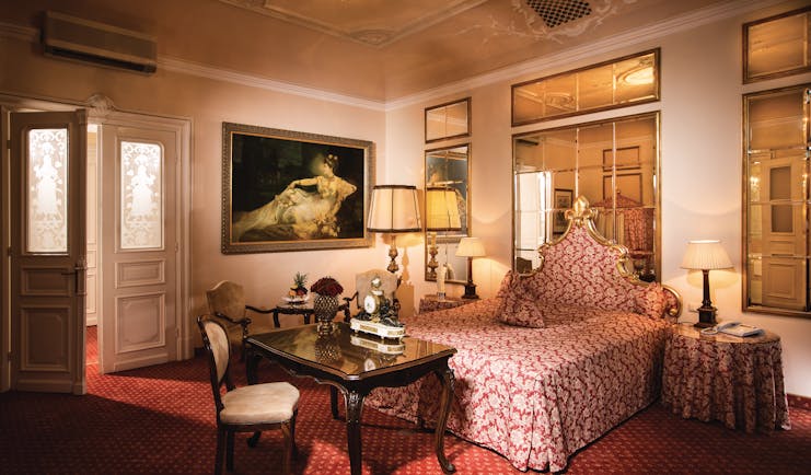 Hotel Bristol Salzburg junior suite with red colour scheme, large mirrors and gold framed paintings
