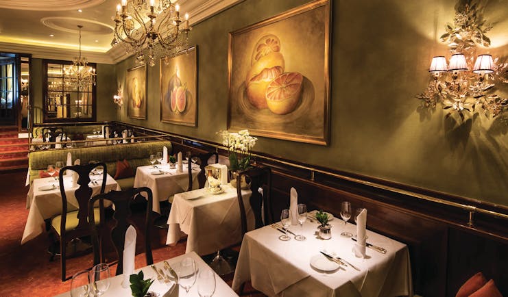 Hotel Bristol Salzburg restaurant dining area with green walls, chandeliers and dining tables set up