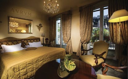 Hotel Bristol Salzburg standard room with green and beige colour scheme, large double bed, arm chairs, mirror and chandelier