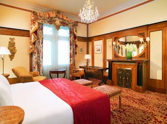 Hotel Bristol Vienna deluxe bedroom cream walls and wood panels armchair and chandelier