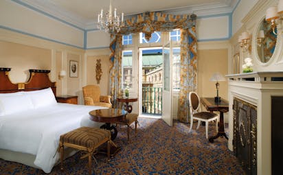 Hotel Bristol Deluxe room with double bed and seating throughout the room and a fireplace in front of the bed