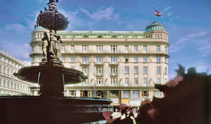 Hotel Bristol Vienna exterior fountain with sculptures of people overlooking large cream building
