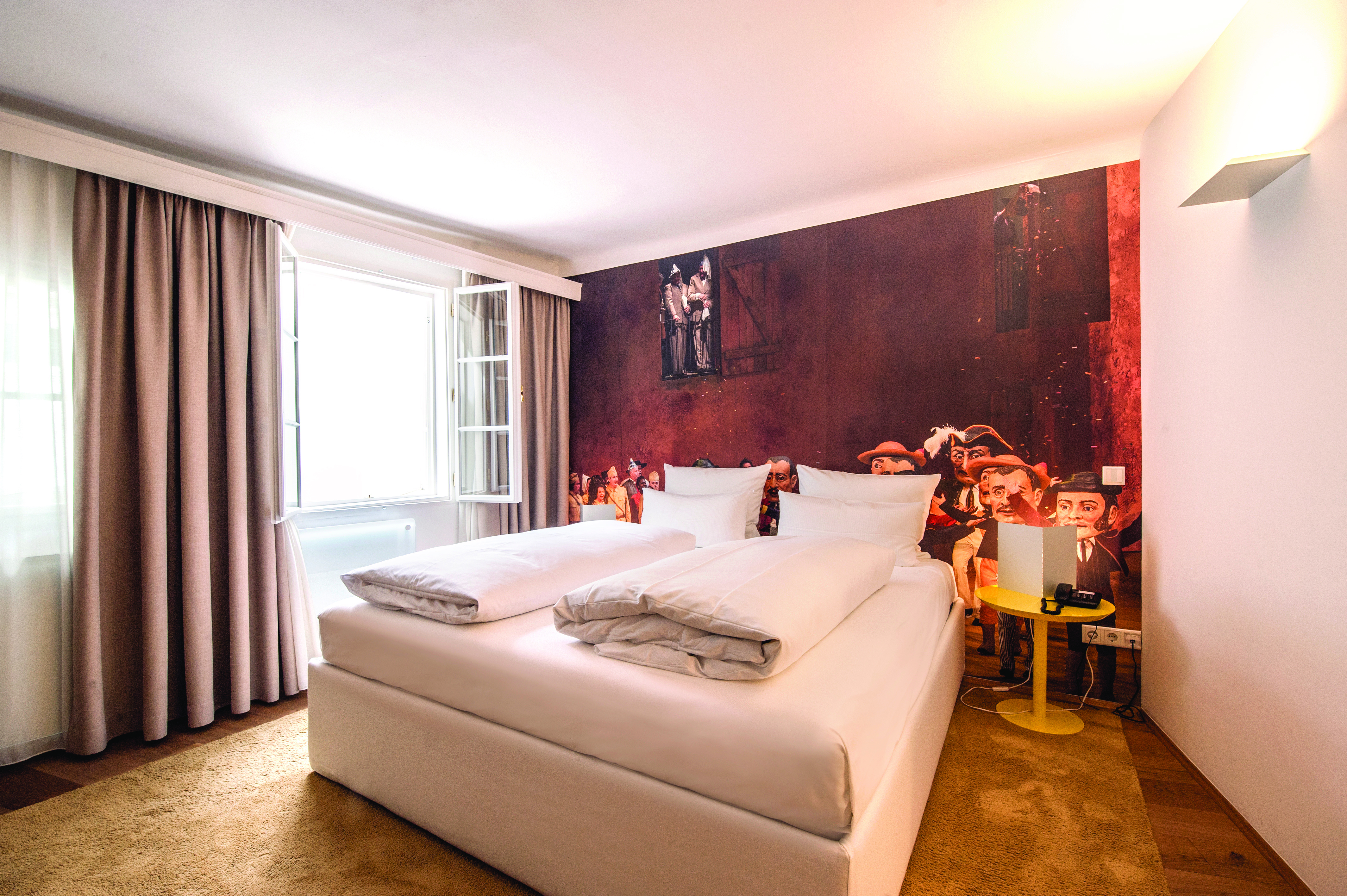 Hotel Goldgasse double bed within a spacious room and a red back wall with a light brown floor