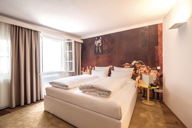 Hotel Goldgasse double bed within a spacious room and a red back wall with a light brown floor