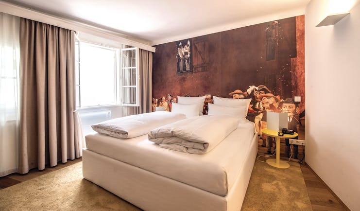 Hotel Goldgasse double bed within a spacious room and a red back wall with a light brown floor