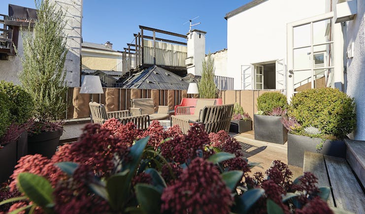 Hotel Goldgasse exterior seating area with flowers placed around the chairs and benches