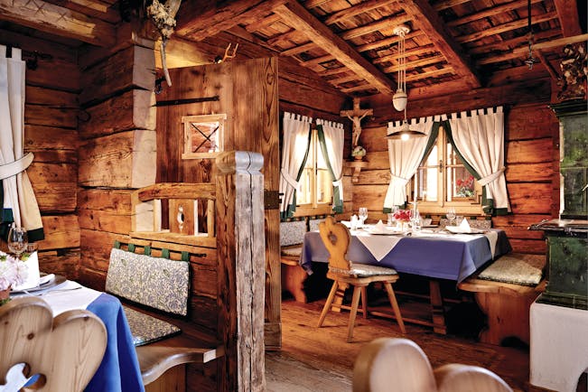 Dining area with wood pannelled ceiling, floor and walls and dining tables set up around the room 