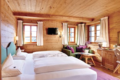 Standard room with wood pannelled ceiling, walls and floors with double bed and small windows