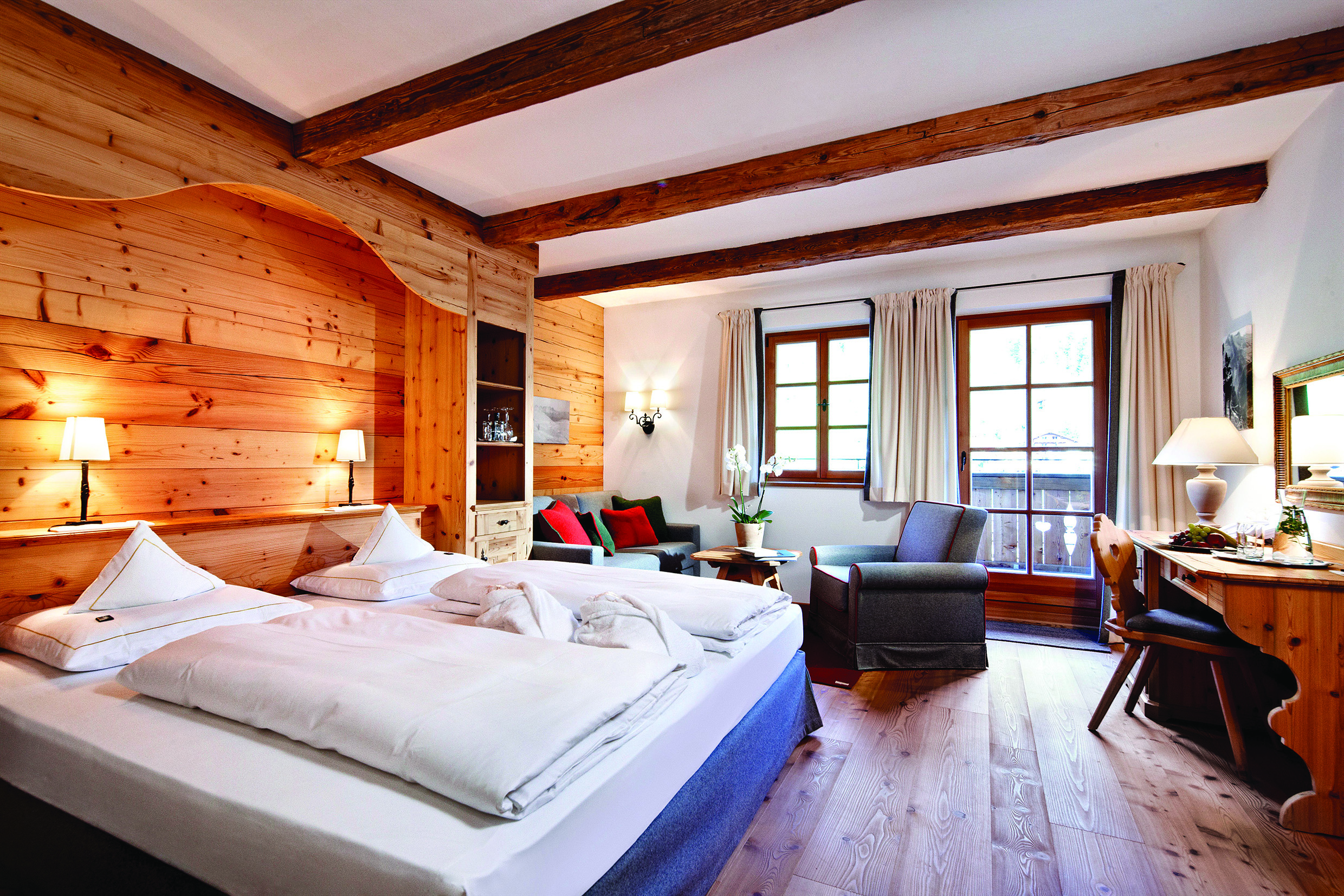 Superior room with wood pannelled walls and floor, large double bed and large windows 
