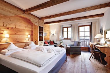 Superior room with wood pannelled walls and floor, large double bed and large windows 