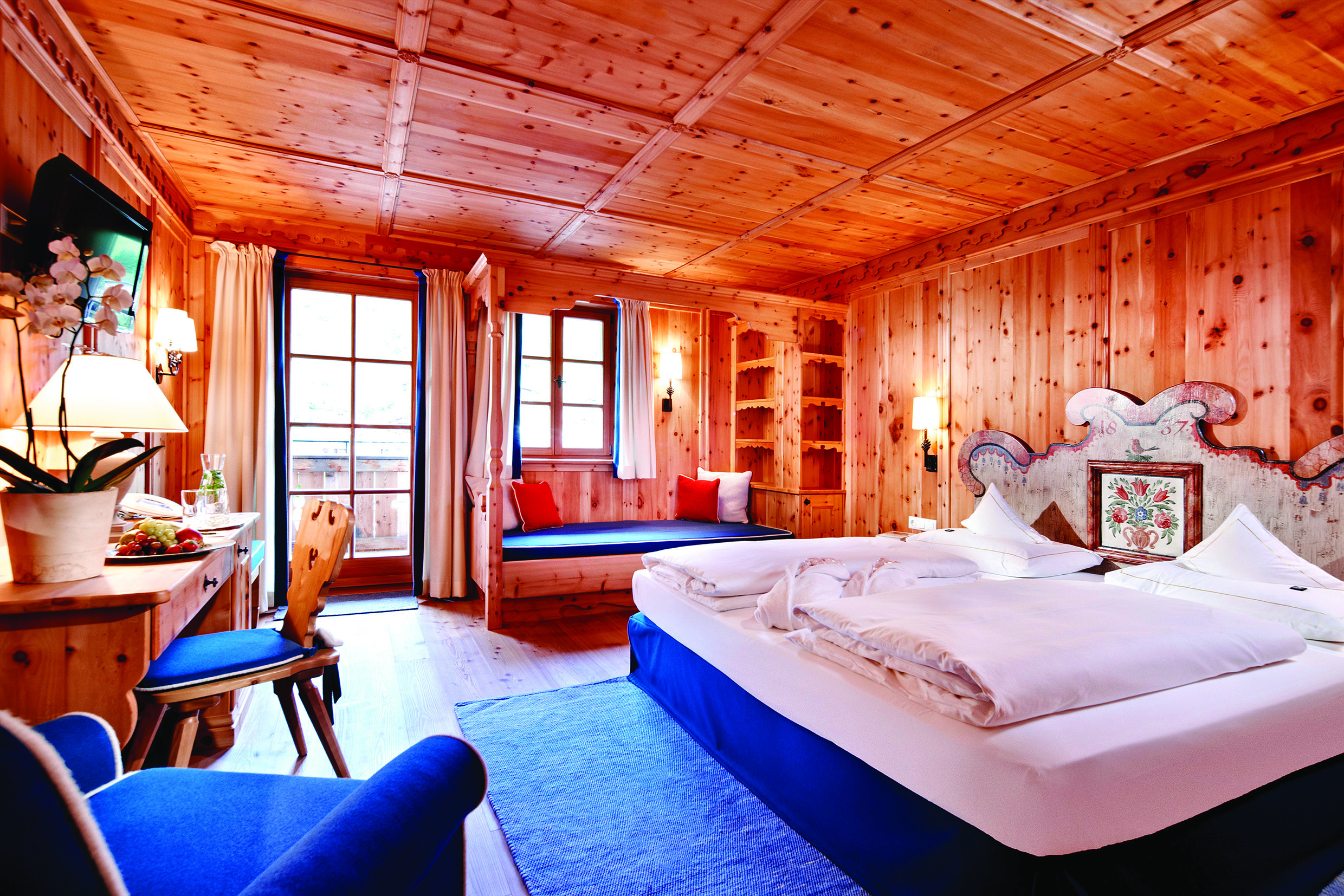 Superior suite with wood pannelled ceiling, floor and walls, with large double bed and large windows 