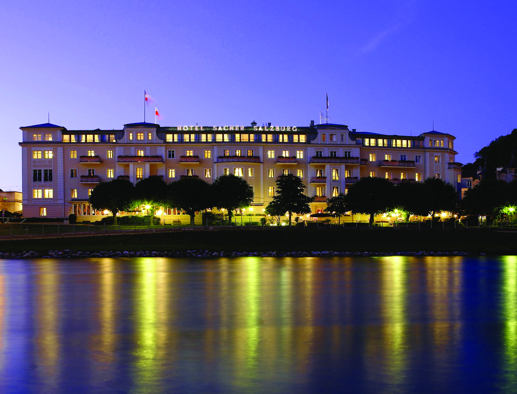 Hotel Sacher hotel exterior, grand style building at twilight, lit up, overlooking river