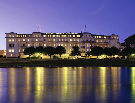 Hotel Sacher hotel exterior, grand style building at twilight, lit up, overlooking river