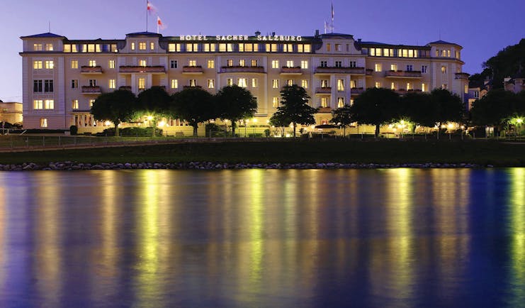 Hotel Sacher hotel exterior, grand style building at twilight, lit up, overlooking river