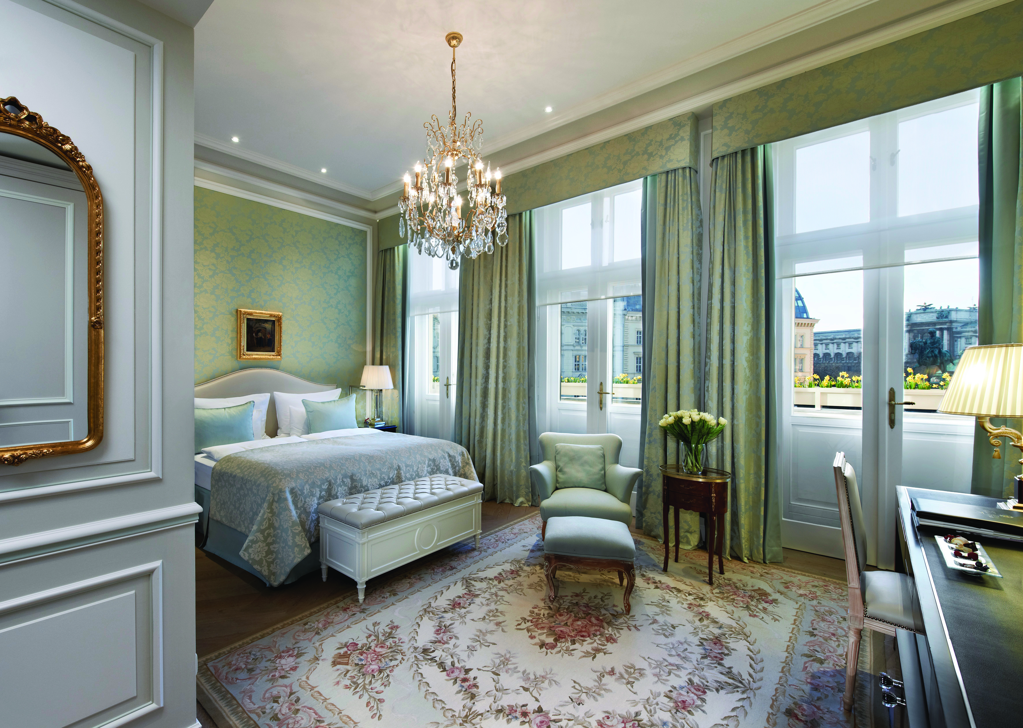 Hotel Sacher Vienna deluxe bedroom ornate mirror chandelier armchair with footstool and large windows