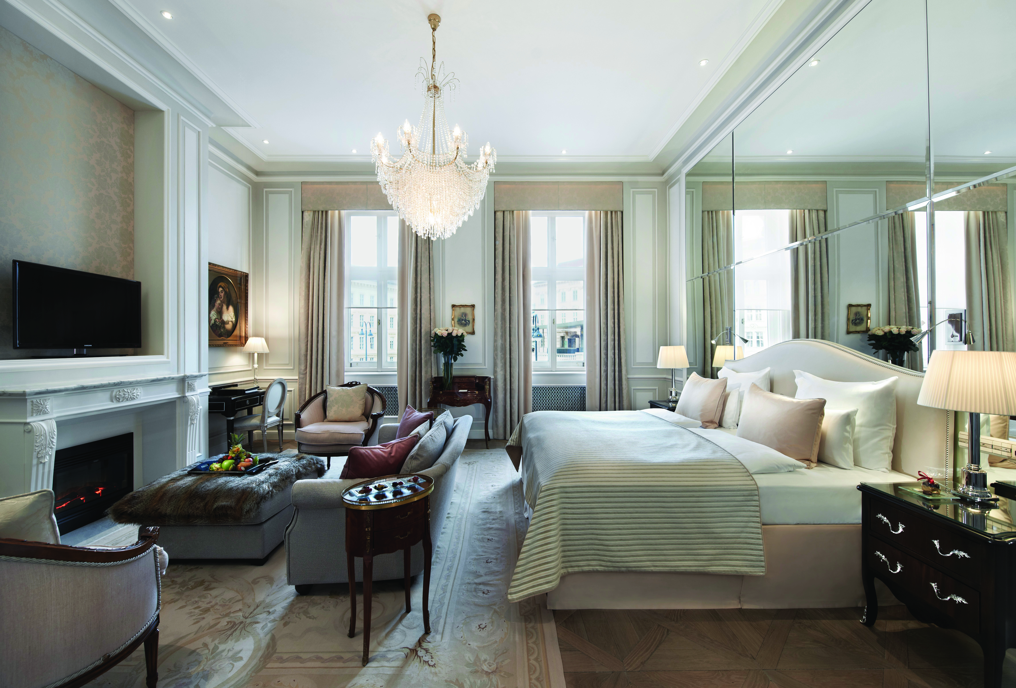 Hotel Sacher Wien Deluxe Junior Suite with a double bed and a hanging light and chairs and tables next to a fireplace