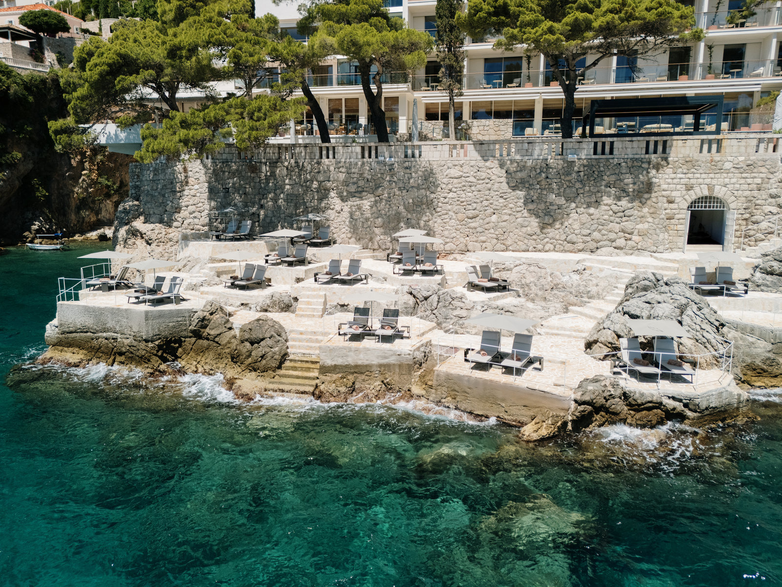 Villa Dubrovnik beachfront with rocky terraces, steps into the sea, and the hotel building above