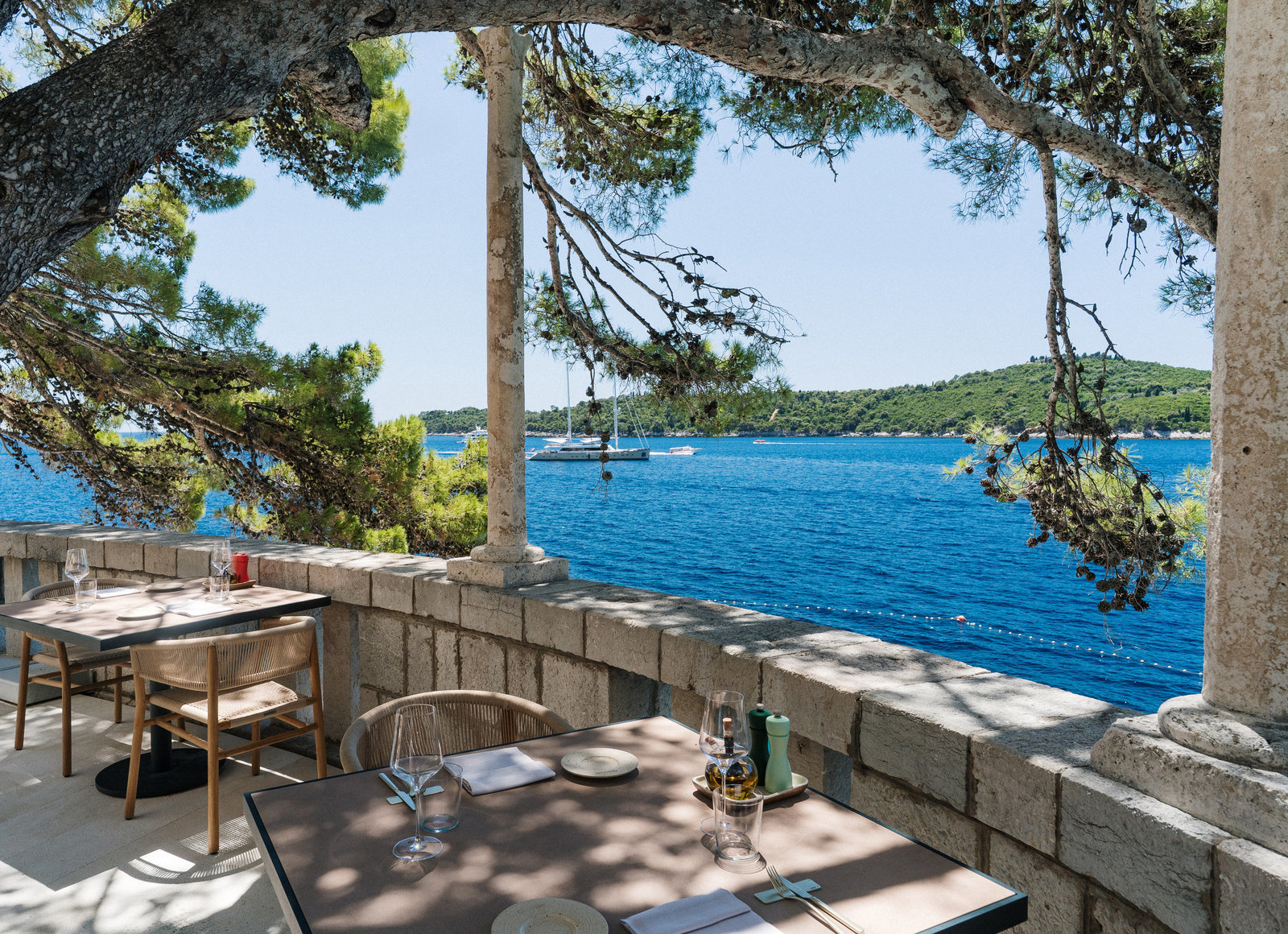 Villa Dubrovnik garden terrace, with stone walls, pillars, tables and chairs overlooking the sea