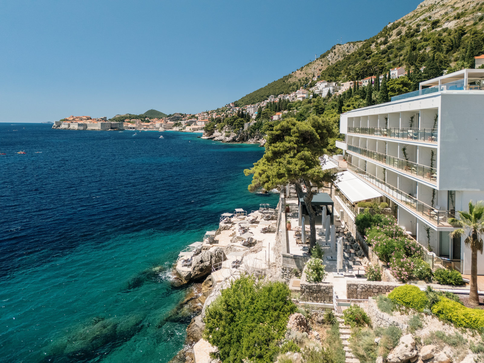 Villa Dubrovnik exterior side view, showing the rocky coastline and clear turquoise sea