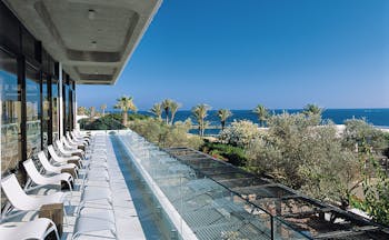 Almyra Hotel Cyprus terrace balcony with loungers overlooking trees and sea