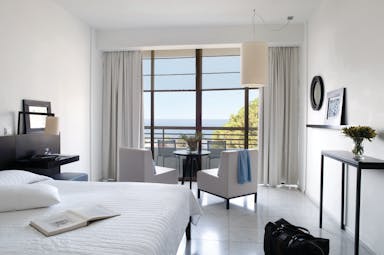 Bedroom at Almyra Hotel with balcony showing sea view, large double bed and seating area