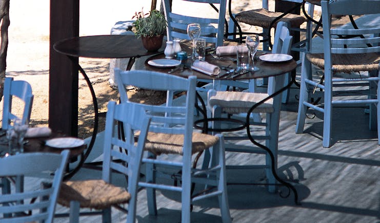 Outdoor dining terrace with white and wooden tables and chairs set out 