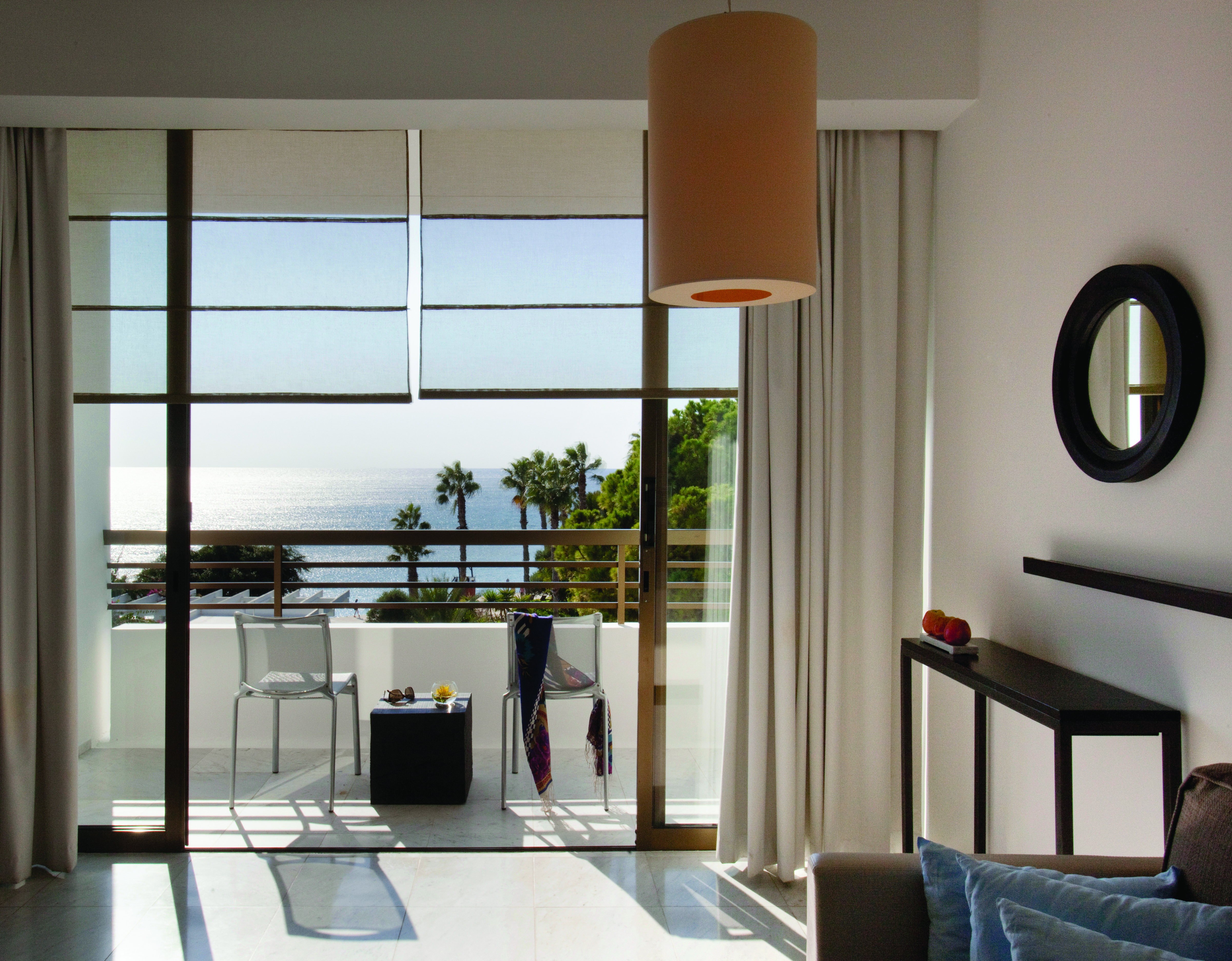 Sea view from bedroom showing balcony with table and chairs on looking over palm trees and seas