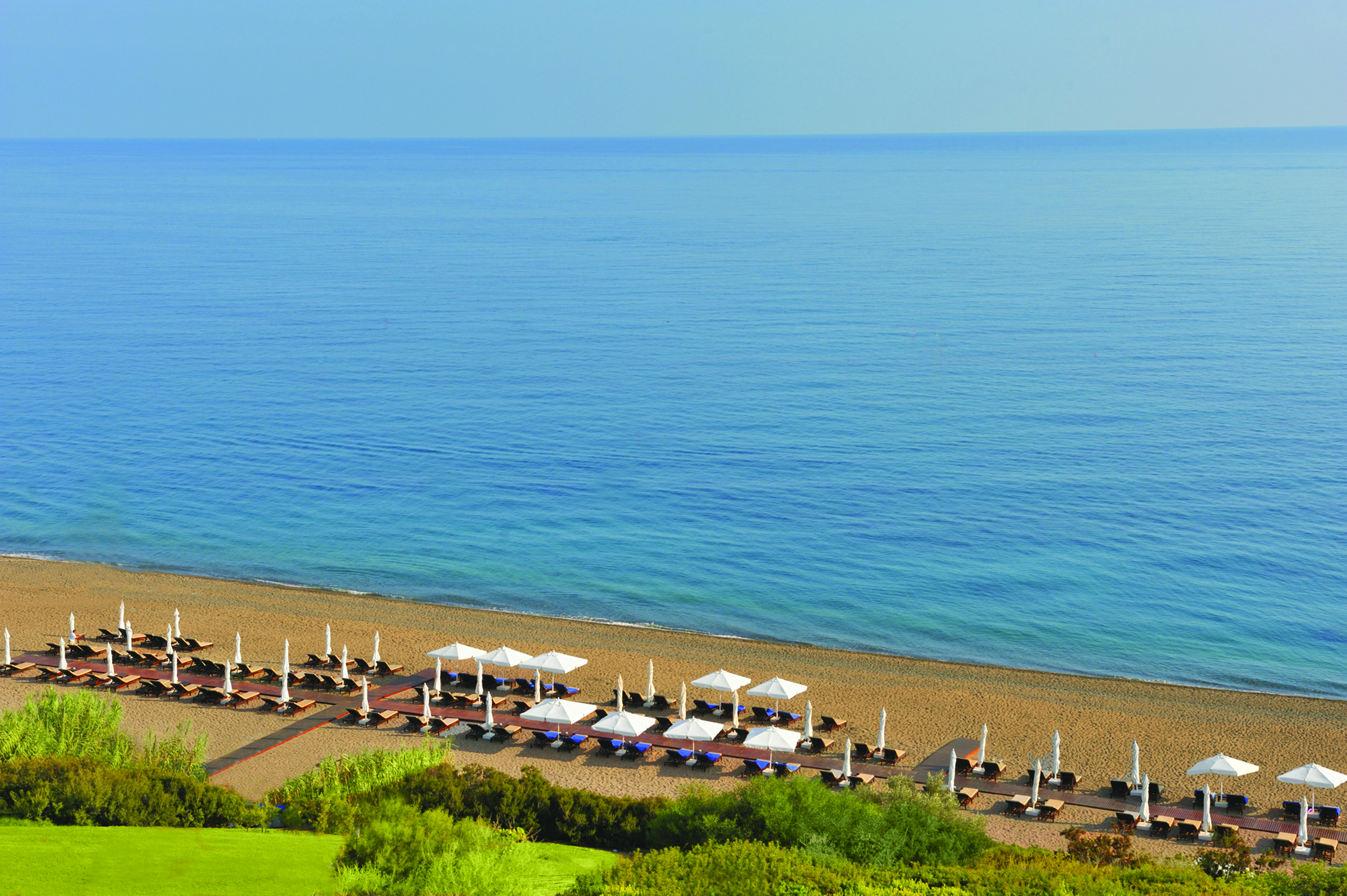 Anassa Hotel view of the beach from above with deck chairs laid out on the beach 