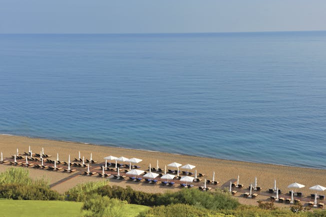 Anassa Hotel view of the beach from above with deck chairs laid out on the beach 
