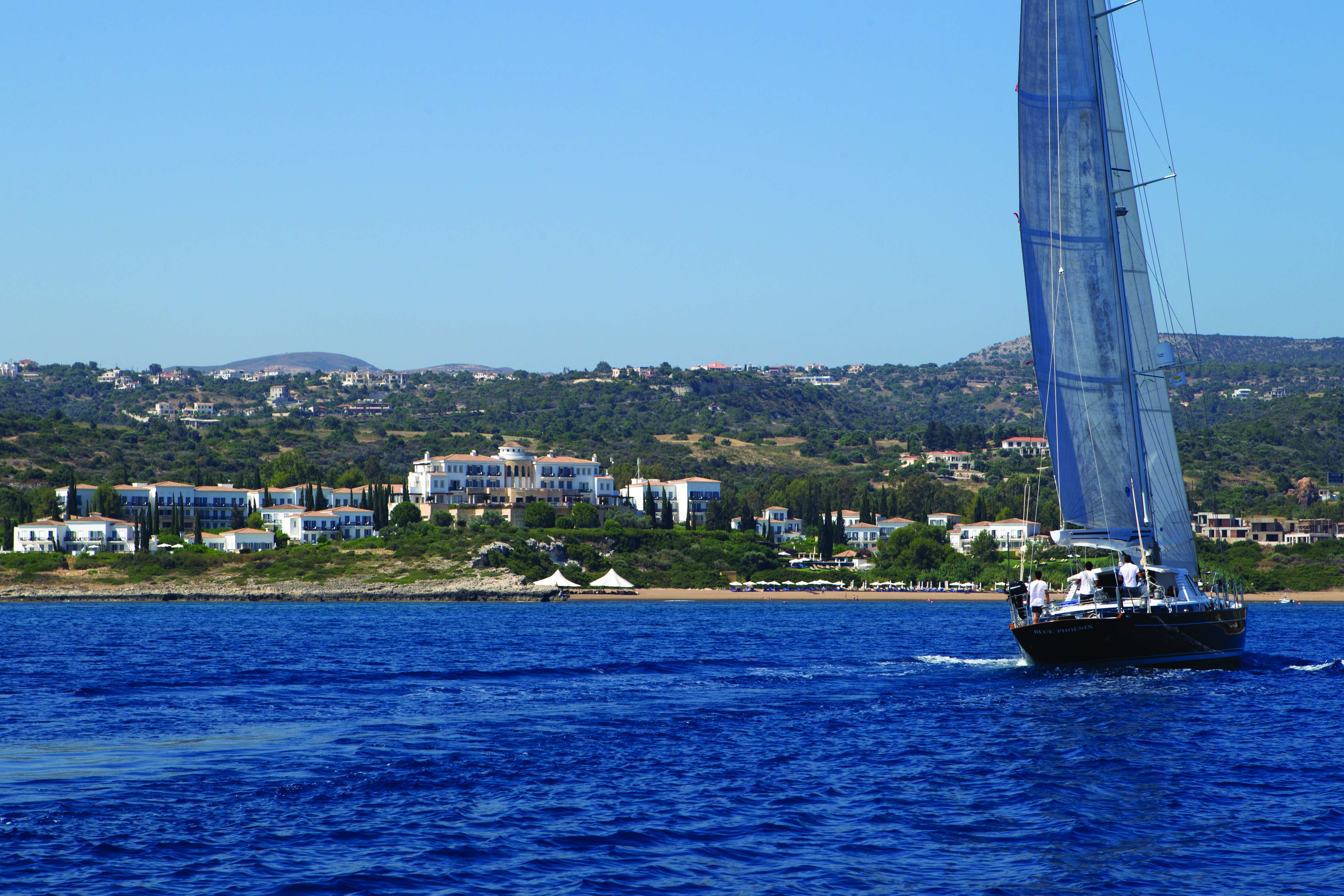 View of the Anassa Hotel from the sea with a sail boat out in front