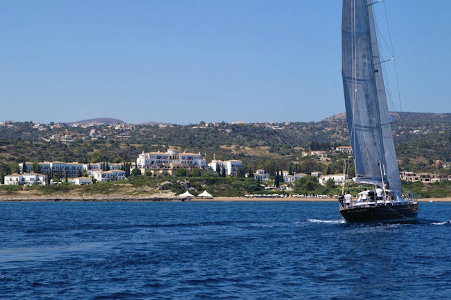 View of the Anassa Hotel from the sea with a sail boat out in front