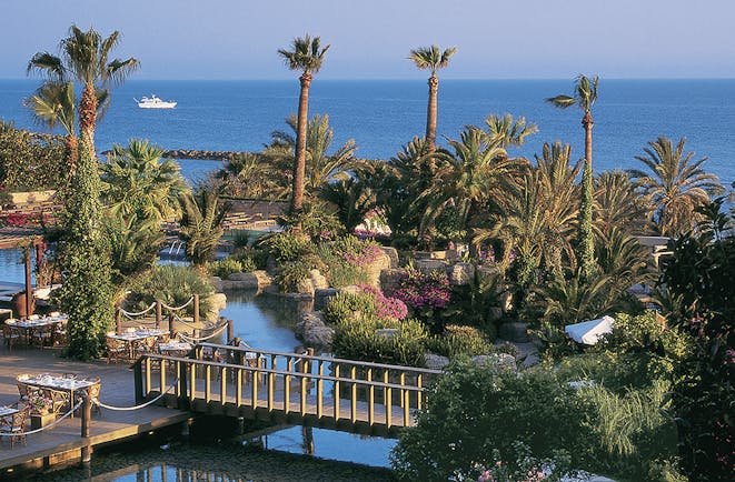 Annabelle Hotel Cyprus exterior panorama of hotel grounds with palm trees flowers and a bridge with sea views