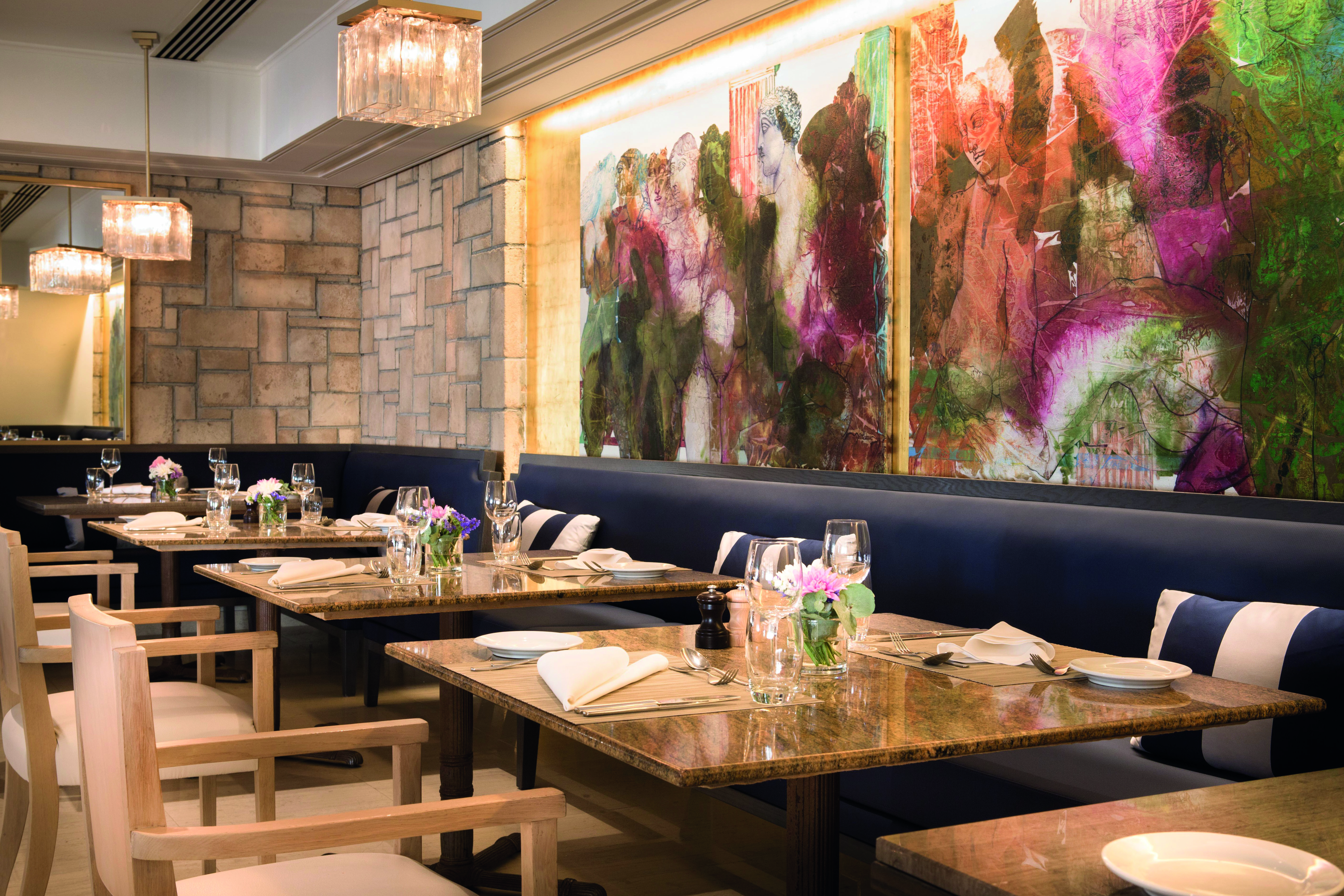 Annabelle Hotel Cyprus Amorosa indoor dining area with blue benches and seats and wall painting