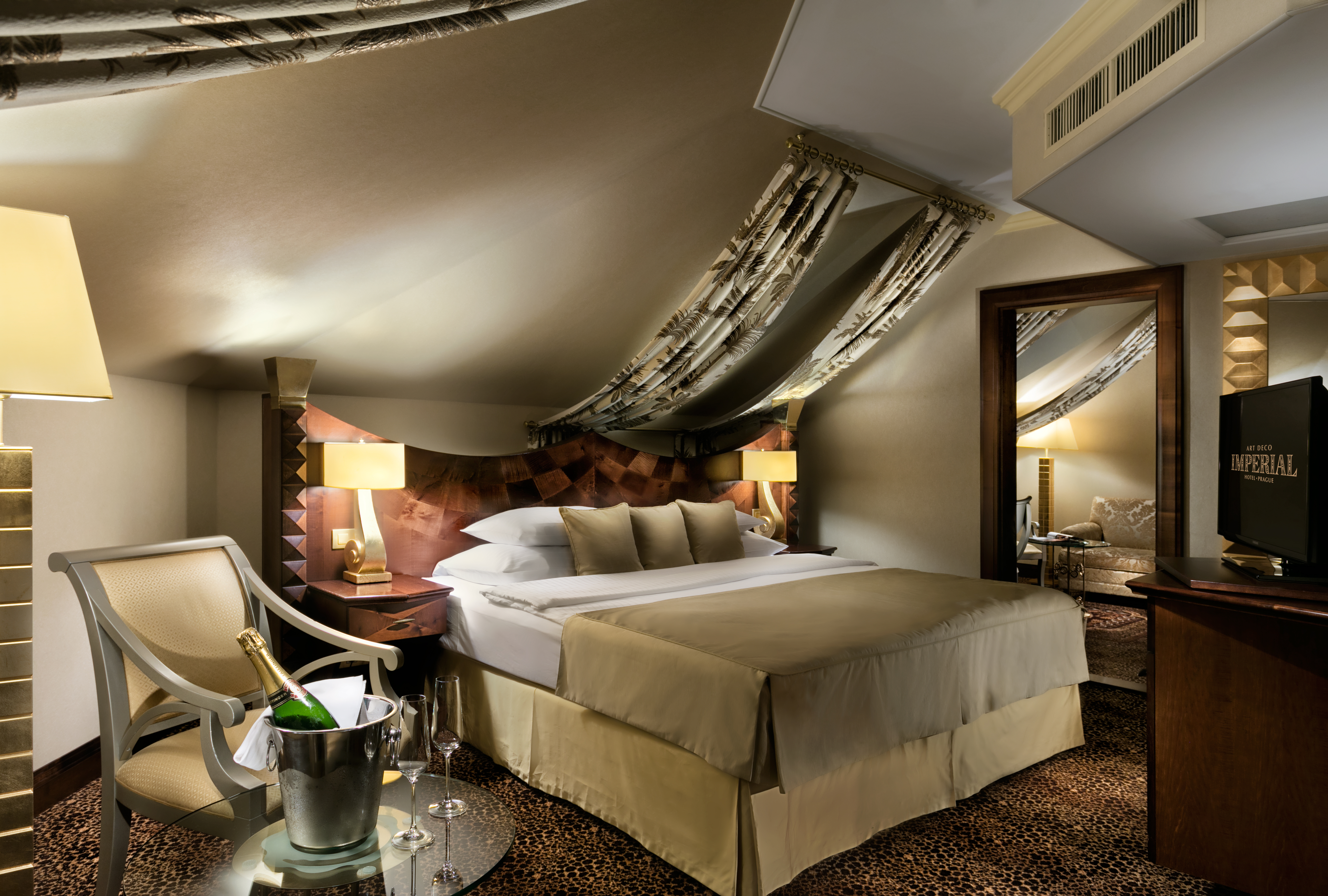 Executive suite with large double bed, arm chair, a television and lamp shades