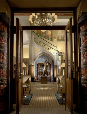 Entrance to hotel with high ceiling, large chandelier and statues