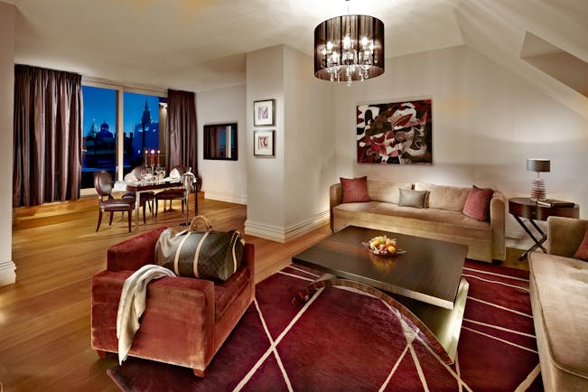 Grand Mark Prague Bohemia suite lounge area, armchairs and sofa, table and chairs, large windows with city views, colourful decor
