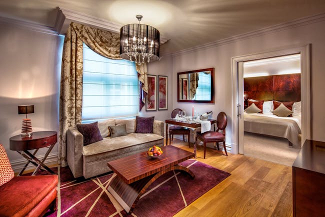 Grand deluxe room with large bed, sofa chandelier and coffee table