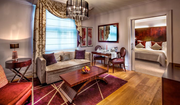 Grand deluxe room with large bed, sofa chandelier and coffee table