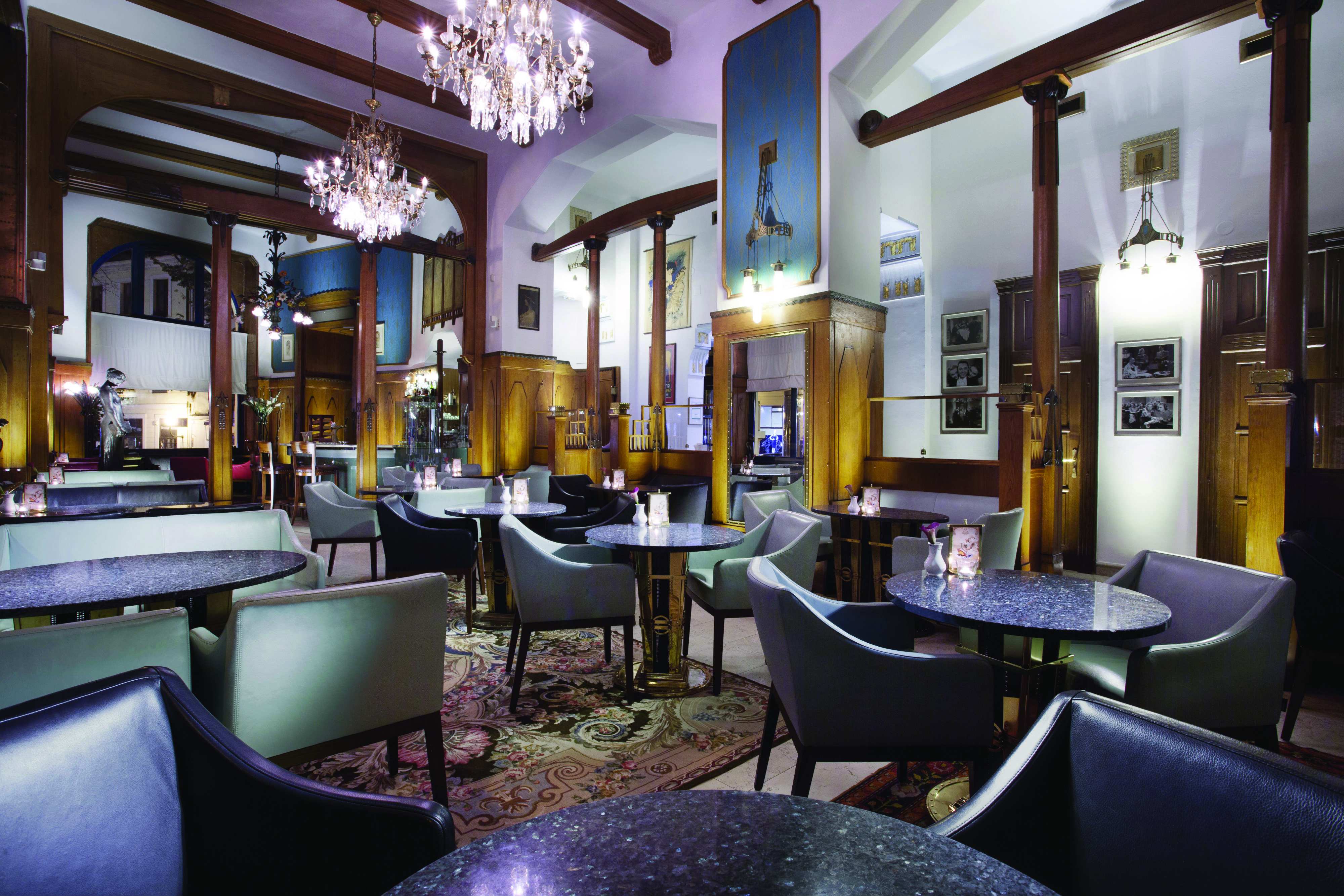 Hotel Paris Prague cafe large room with wooden beams and panels chandeliers and several chairs