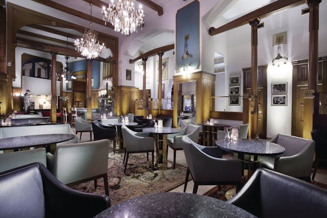 Hotel Paris Prague cafe large room with wooden beams and panels chandeliers and several chairs