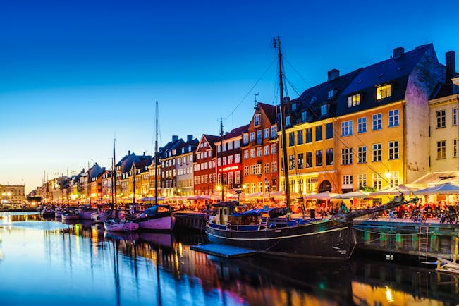 Evening picture with illuminated houses by edge of water