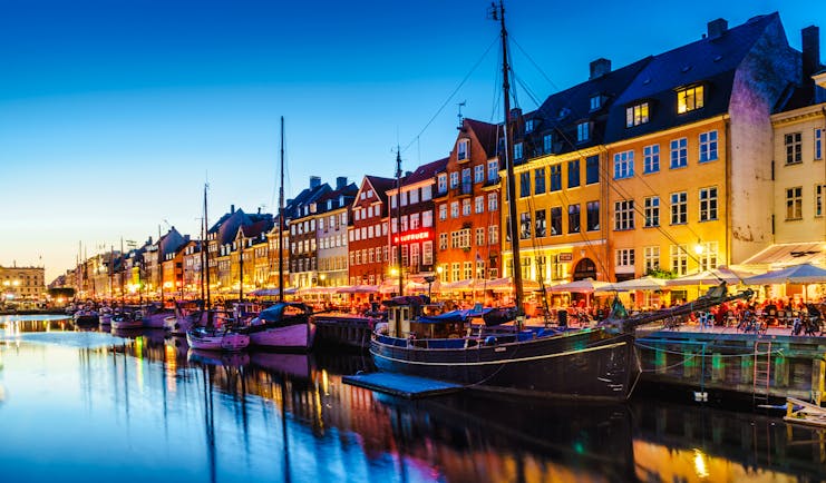 Evening picture with illuminated houses by edge of water