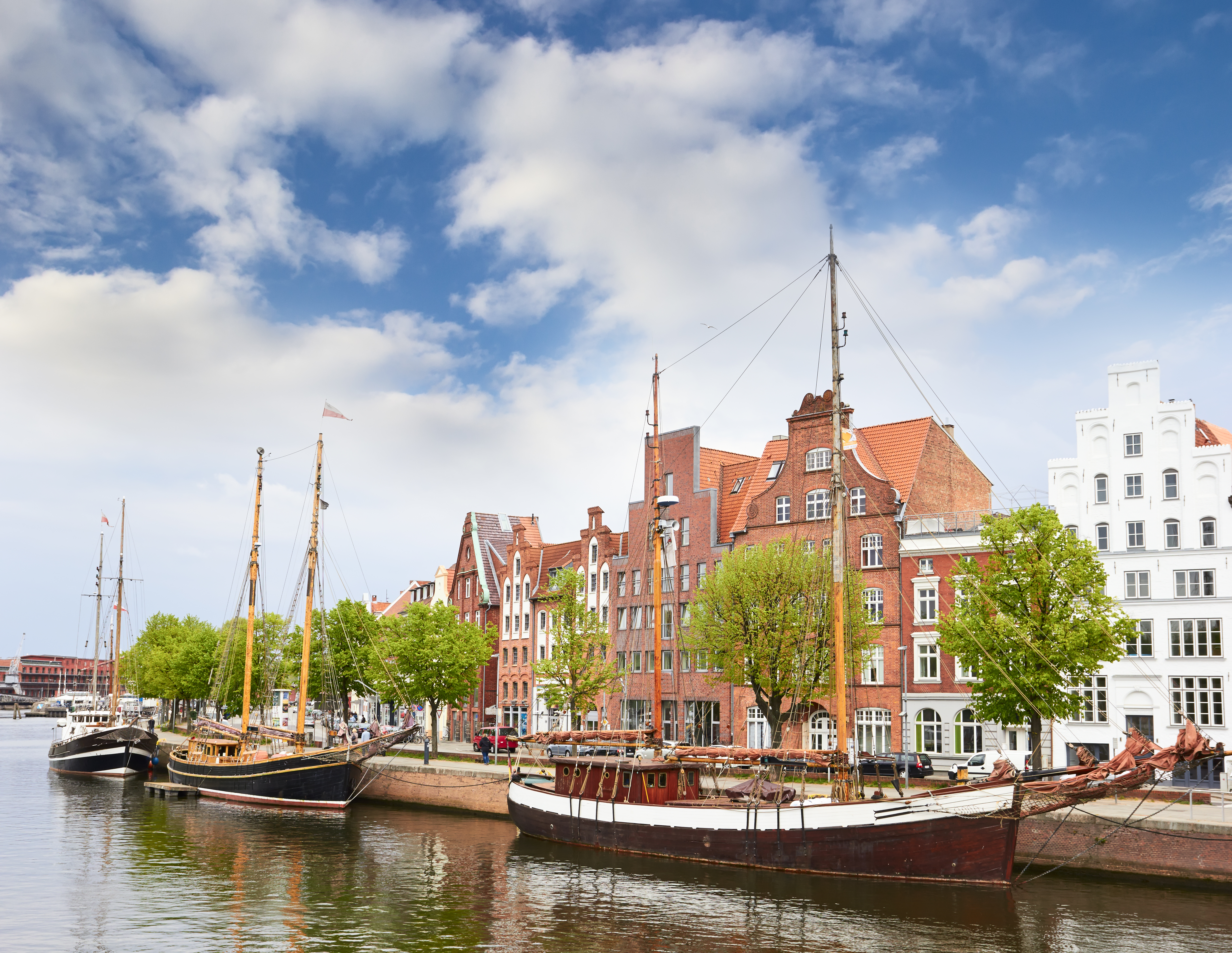 Wooden boats moored on river by old warehouses in Lubeck